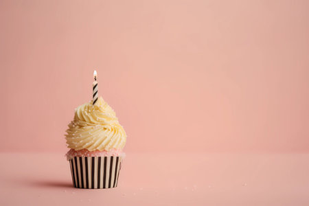 Birthday cupcake with a lit candle on a light pink background with copy space, generative AIの素材