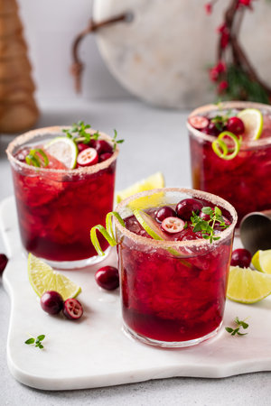 Christmas cranberry and lime margarita cocktail garnished with lime zest swirlの写真素材