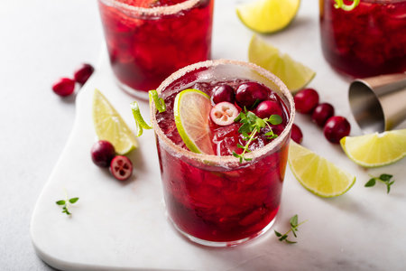 Christmas cranberry and lime margarita cocktail garnished with lime zest swirlの写真素材