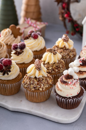 Variety of Christmas cupcakes on a marble tray with gingerbread, cranberry, pecan nuts and hot chocolateの写真素材