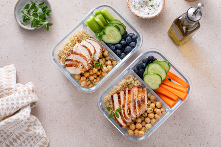 High protein healthy lunch meal prep in containers with chicken, quinoa, herbed chickpeas, vegetables and eggsの写真素材