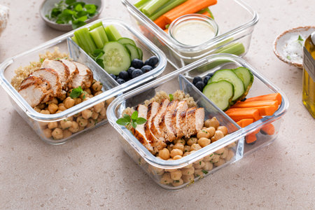 High protein healthy lunch meal prep in containers with chicken, quinoa, herbed chickpeas,...