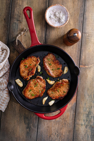 Pork chops cooked with garlic in a cast iron panの写真素材