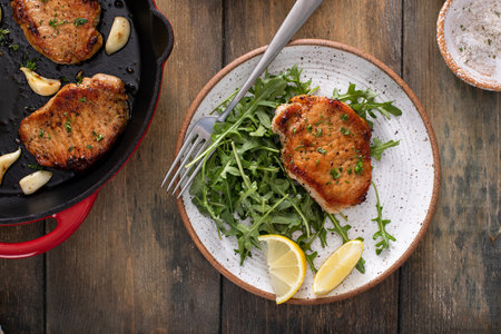 Pork chops cooked with garlic served with arugula salad on a plateの写真素材