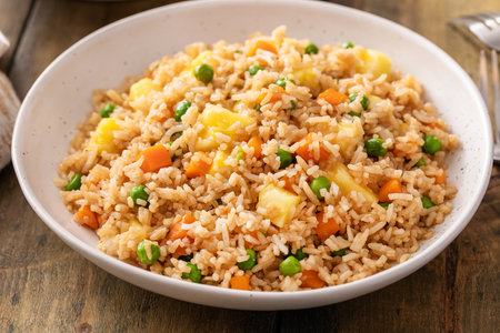 Pineapple fried rice with eggs, carrots and peas in a white bowlの写真素材