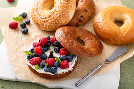 Cinnamon raisin bagel topped with cream cheese and fresh berries for breakfastの写真素材