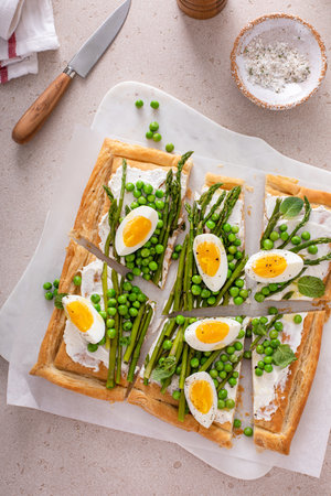 Asparagus and egg tart with peas, puff pastry and cream cheese, spring recipe ideaの写真素材