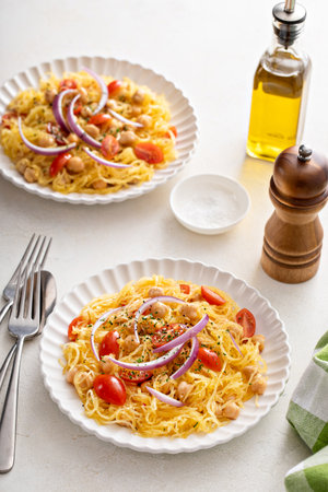 Spaghetti squash with chickpeas and tomatoes topped with red onion, low carb and vegan recipe ideaの写真素材