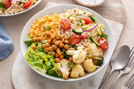 Vegan lunch bowl with roasted vegetables, fresh lettuce, cooked lentils, couscous salad and crunchy roasted chickpeasの写真素材