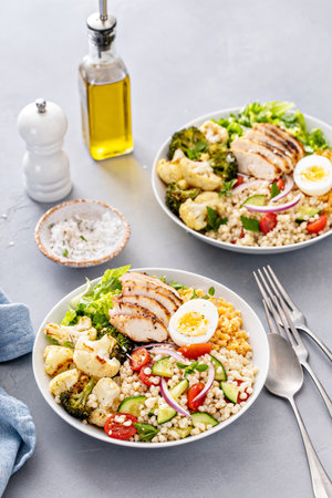 Healthy lunch bowl with grilled chicken, roasted vegetables, fresh lettuce, cooked lentils, couscous salad and hard boiled eggの写真素材