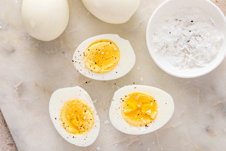 Hard boiled eggs peeled and cut in half with salt and pepperの写真素材