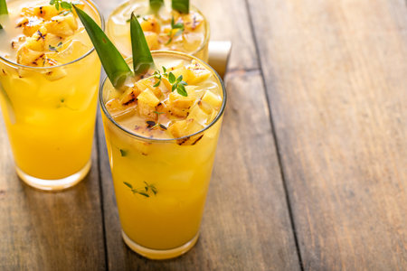 Grilled pineapple cocktail or mocktail garnished with pineapple leaves and thymeの写真素材