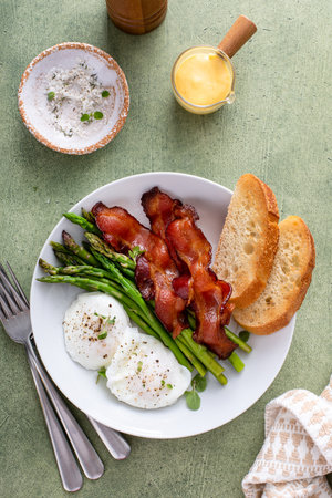 Poached eggs with bacon and asparagus for breakfast served with toastの写真素材