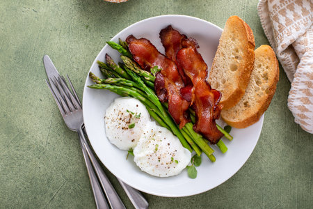 Poached eggs with bacon and asparagus for breakfast served with toastの写真素材