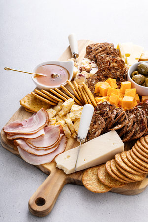 Charcuterie board or cheese and snacks board with crackers, honey and olivesの写真素材