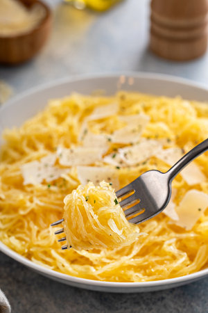 Spaghetti squash roasted and pulled apart served with olive oil and parmesan, low carb recipe idea, with a fork swirled inの写真素材
