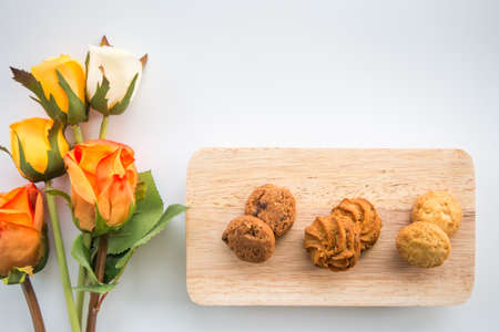 Top view assorted cookies on wooden boards White background and rose. Chocolate chip cookies, Raisin cookies, Coconut cookies.の写真素材