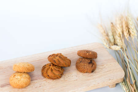 Assorted cookies on wooden boards White background and wheat. Chocolate chip cookies, Raisin cookies, Coconut cookies.の写真素材