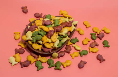 Colorful rainbow goldfish crackers on a pink background