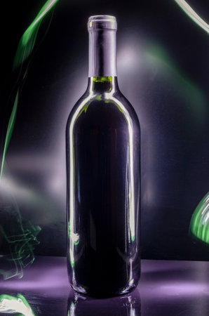 Black bottle of wine on a black background with light rails and reflectionsの写真素材