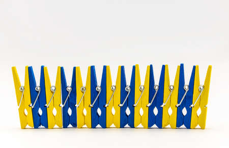 yellow and blue colorful wooden clothespins on a white backgroundの写真素材