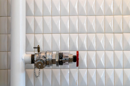 Red metal pipeline valve on the white wallの写真素材