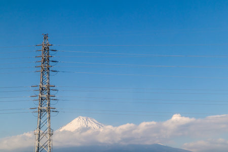 High voltage pole with the wires and Mount Fuji with the cloudsの写真素材