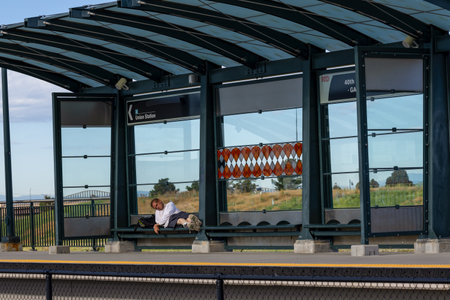 Denver, Colorado - August 2, 2023: A person resting on the bench of the light rail station in...