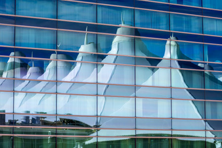 Denver International Airport Architecture Peaks against blue sky reflected in the glass wall