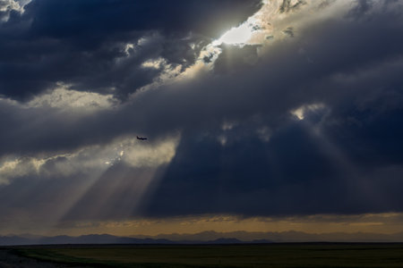 An airplane flying in the stormy sky above the Colorado prairies with the Rocky Mountains visible in...