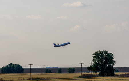An airplane flying in the sunset sky above the Colorado prairies with the Rocky Mountains visible in the distanceの写真素材