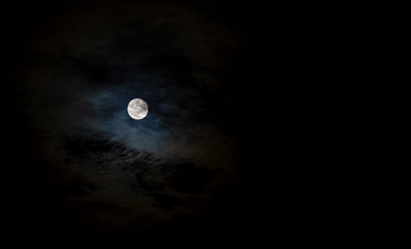 Full September Supermoon against the black cloudy night sky