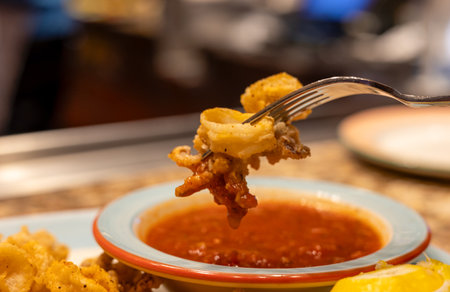 Calamari rings with a slice of lemon, a fork, and a tomato sauce. Close-up, selective focus.の写真素材