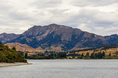 Lake Wanaka, a summer cloudy afternoon with a mountain range and the town of Wanaka on the shore. South Island, New Zealandの写真素材