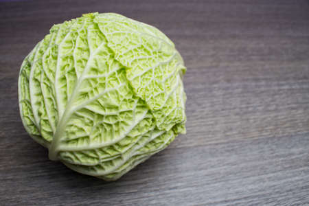 Whole Savoy cabbage with a wooden background