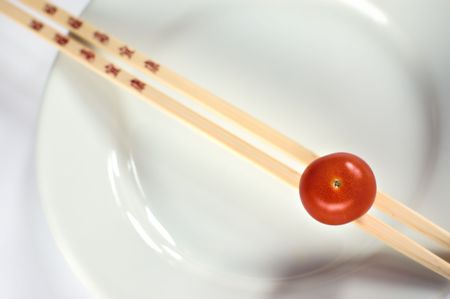 Cherry tomatoe on a white plate with chopsticksの写真素材