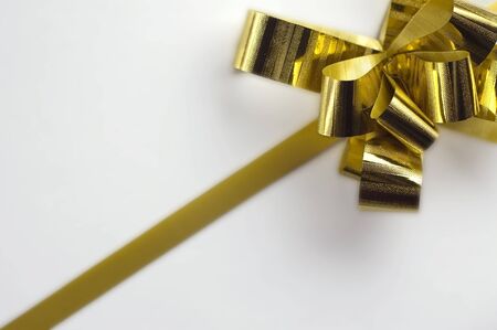 Gift golden ribbon and bow isolated on whiteの写真素材