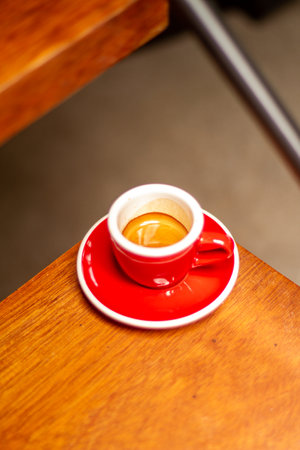 red cup with espresso full of crema under wooden stair in the corner areaの写真素材