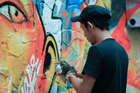 Young man is drawing graffiti art on the wall