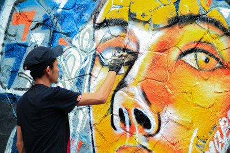 Young man is drawing graffiti art on the wallの写真素材