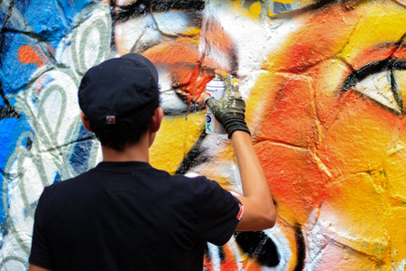 Young man is drawing graffiti art on the wallの写真素材