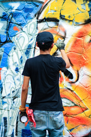 Young man is drawing graffiti art on the wallの写真素材