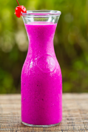 Dragon fruit smoothie or dragon fruit juice in glass jar on table in outdoor tropical cafeの写真素材