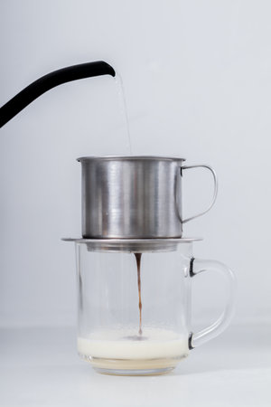 Coffee maker pouring coffee into a glass cup on white backgroundの写真素材