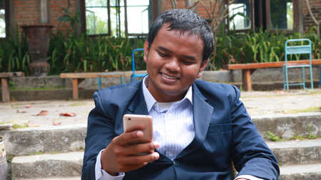 Portrait of an excited young man playing games on mobile phone