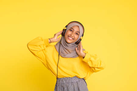 attractive asian woman listening music on yellow background. Woman wearing headset.の写真素材