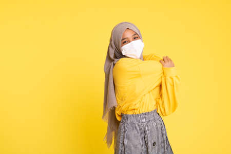 Woman wearing face mask during coronavirus outbreak isolated on yellow background.の写真素材