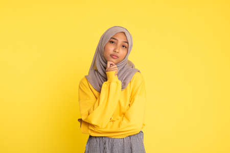Fashion portrait of young beautiful asian muslim woman with wearing hijab isolated on yellow background.の写真素材