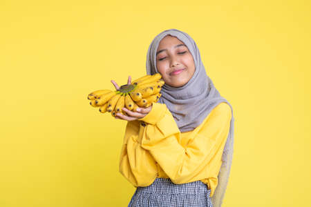 woman making fun with a banana isolated on yellow background.の写真素材