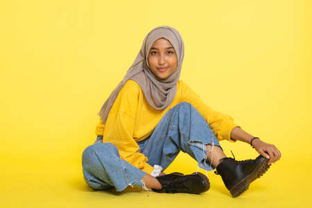 Fashion portrait of young beautiful asian muslim woman with wearing hijab isolated on yellow background.の写真素材